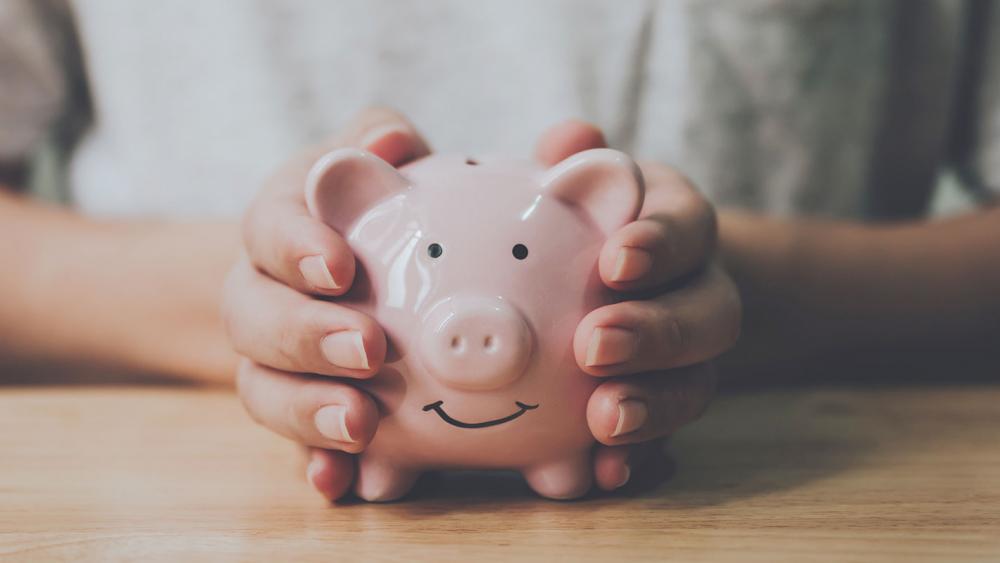 Panoramic image, Man hand holding piggy bank on wood table. Save money and financial investment