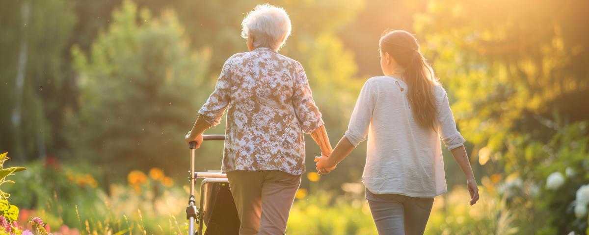 Elderly woman and caretaker taking a tranquil stroll in a sunny garden